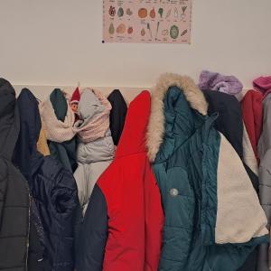 photo du lutin caché dans les manteaux des enfants aux porte-manteaux de la cantine